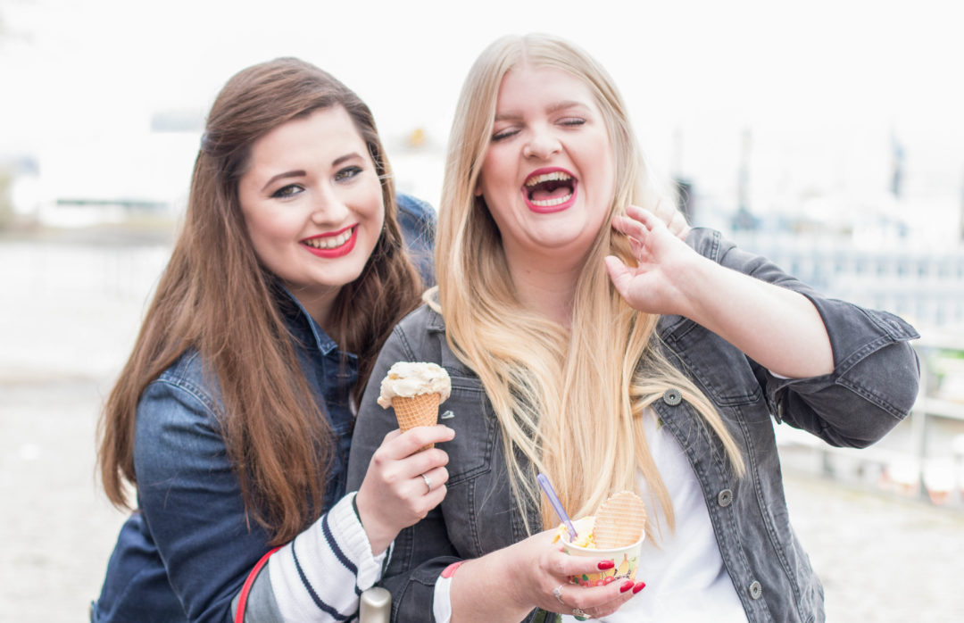 Zwei kurvige Mädchen, Eis essend und lachend in Hamburg